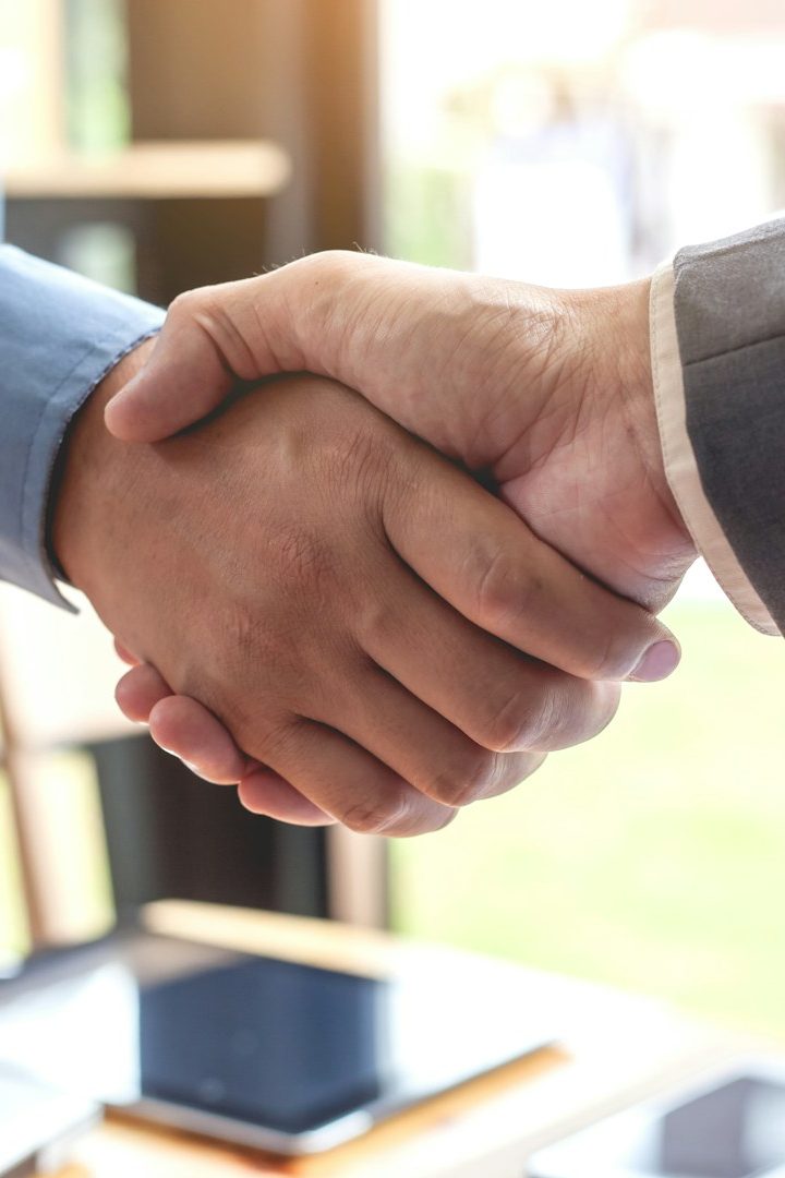 Zwei Personen schütteln sich die Hände in einem hellen, modernen Büro.