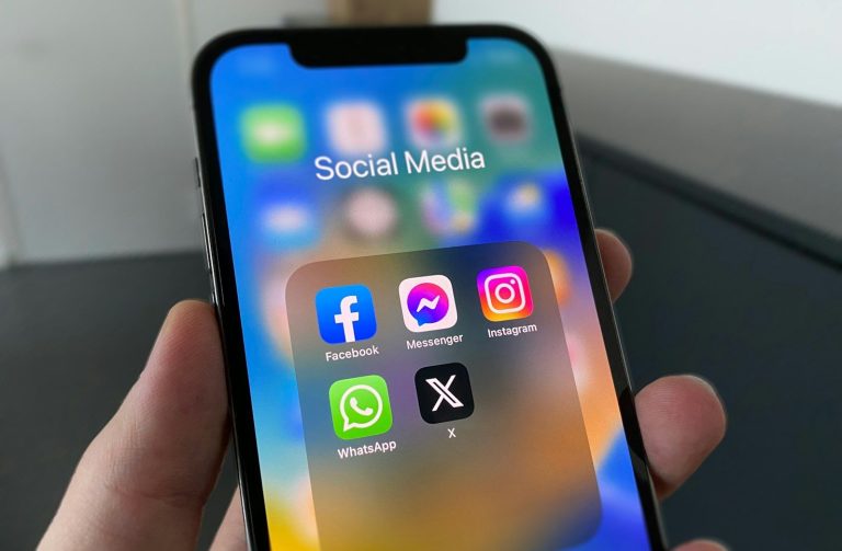 Handy mit Logos der Social Media Kanäle wie Facebook, Instagram, Whatsapp,...